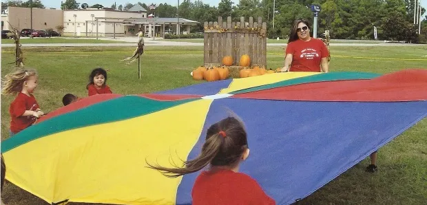 Children playing outdoors with a teacher